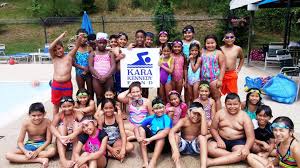 Kara Kennedy Fund kids posing around the sign near a pool